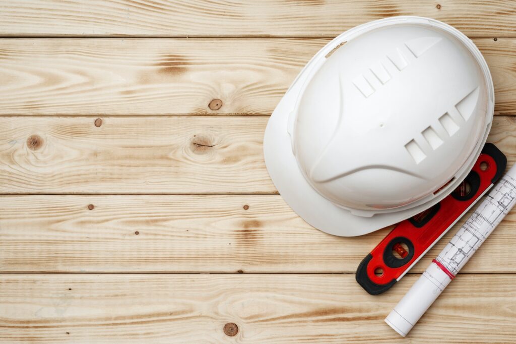 Construction worker hardhat, blueprints and .construction level, top view