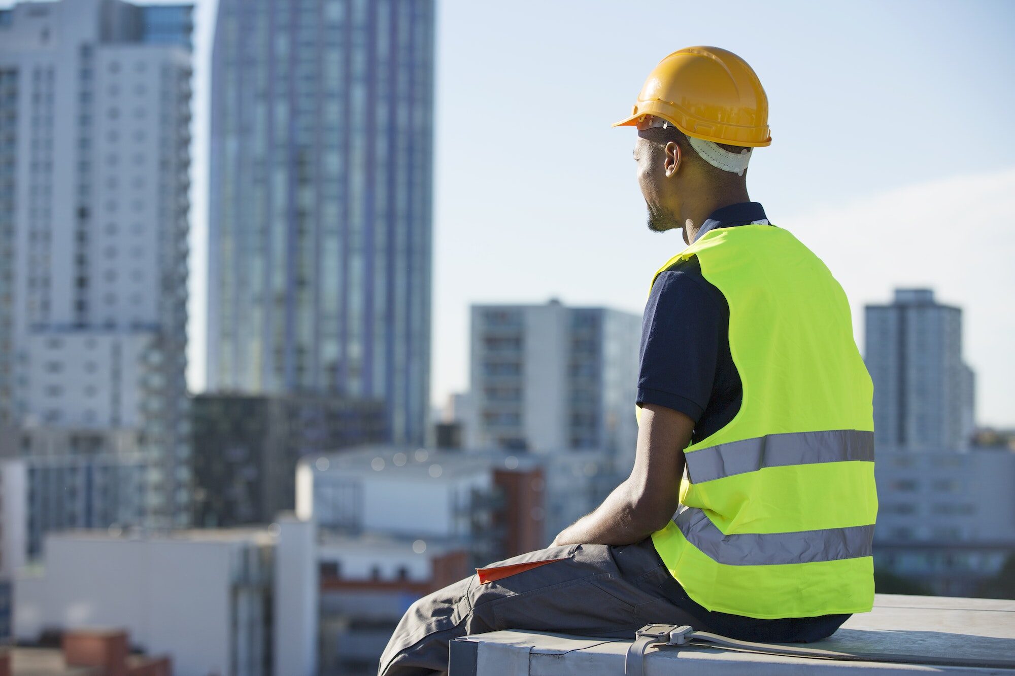 Construction worker sitting on ledge, outdoors, taking a break